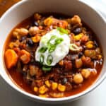 Bowl of vegetarian chili topped with sour cream and chopped green onion.