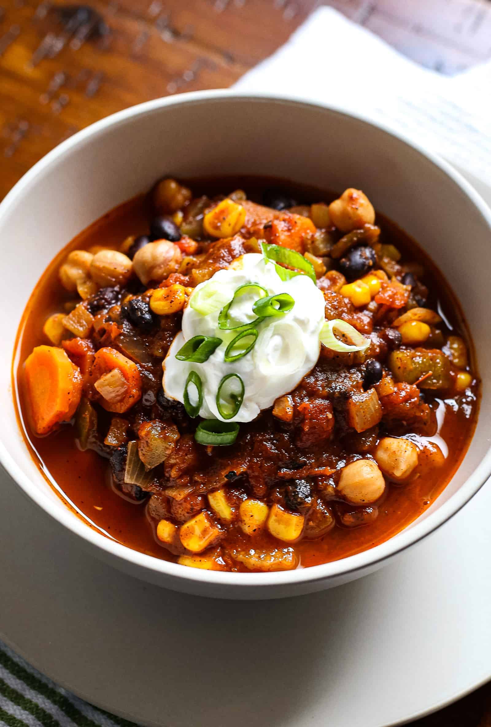 Bowl of vegetarian chili topped with sour cream and chopped green onions.