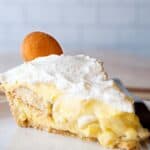 Banana Pudding Pie on a plate. Pie is topped with whipped cream and one Nilla wafer cookie.