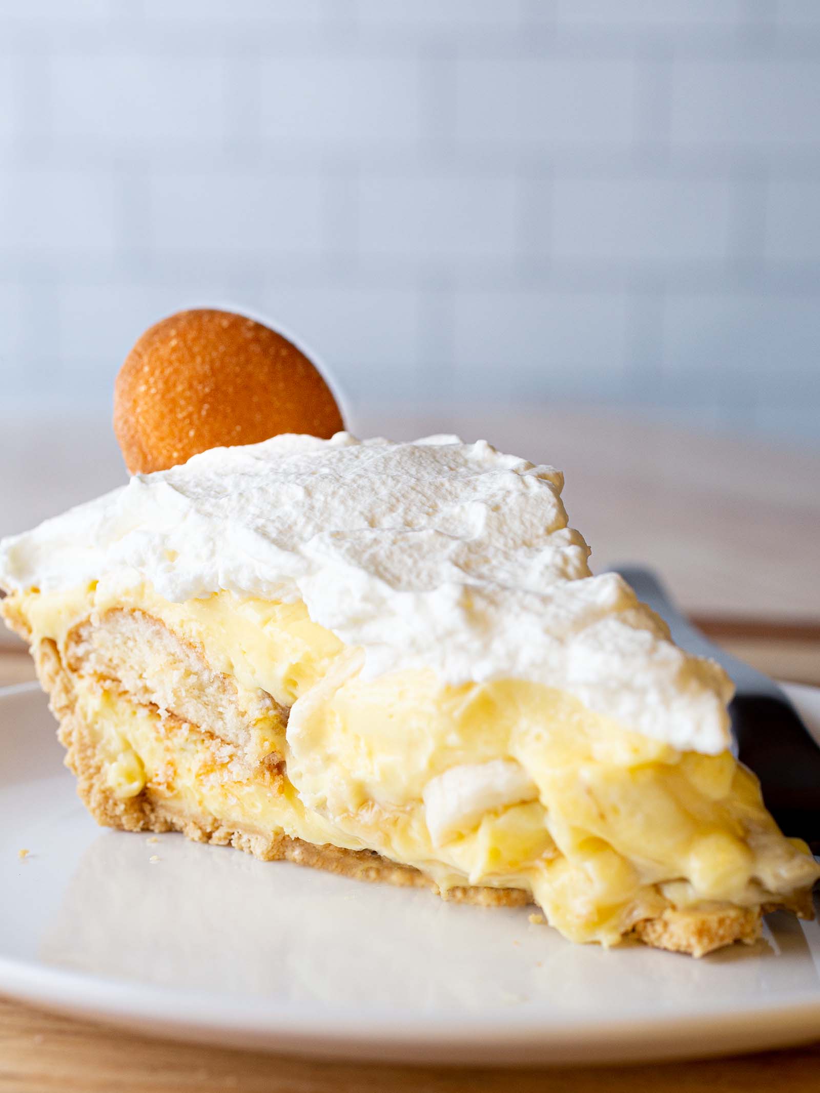 Banana Pudding Pie on a plate. Pie is topped with whipped cream and one Nilla wafer cookie.