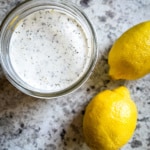 Creamy lemon pepper dressing in a jar. Two lemons are on the side.
