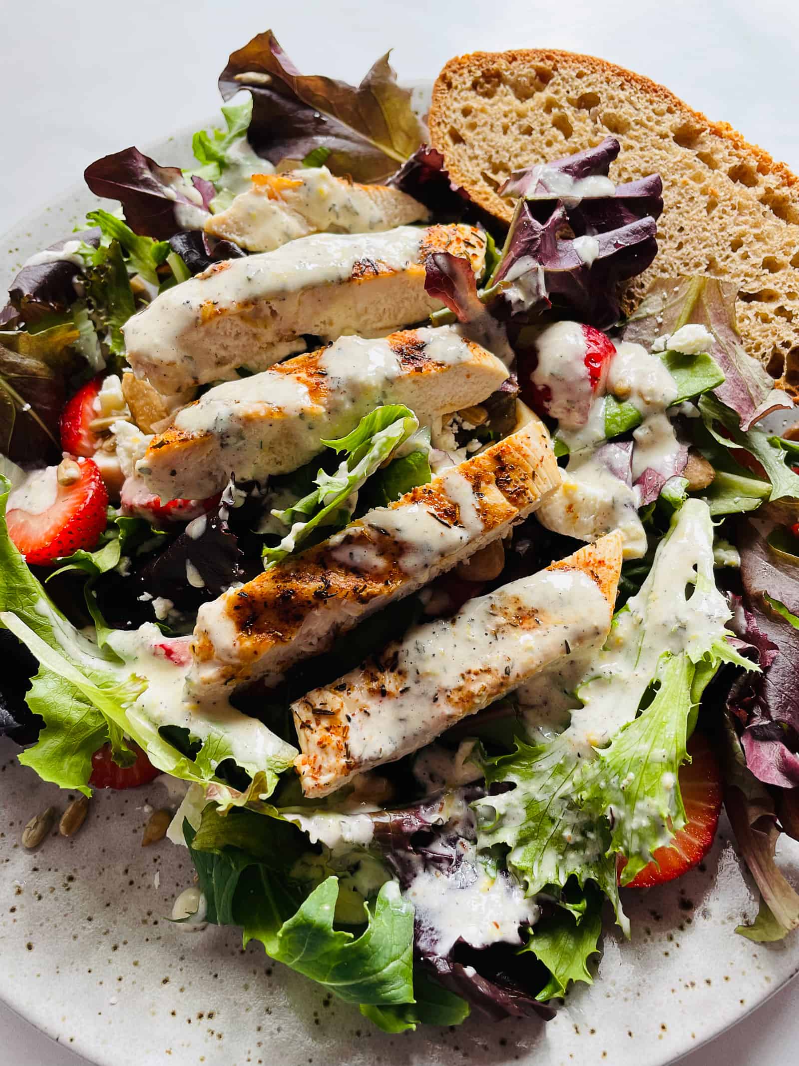 Creamy lemon pepper dressing on a green salad with chicken pieces.