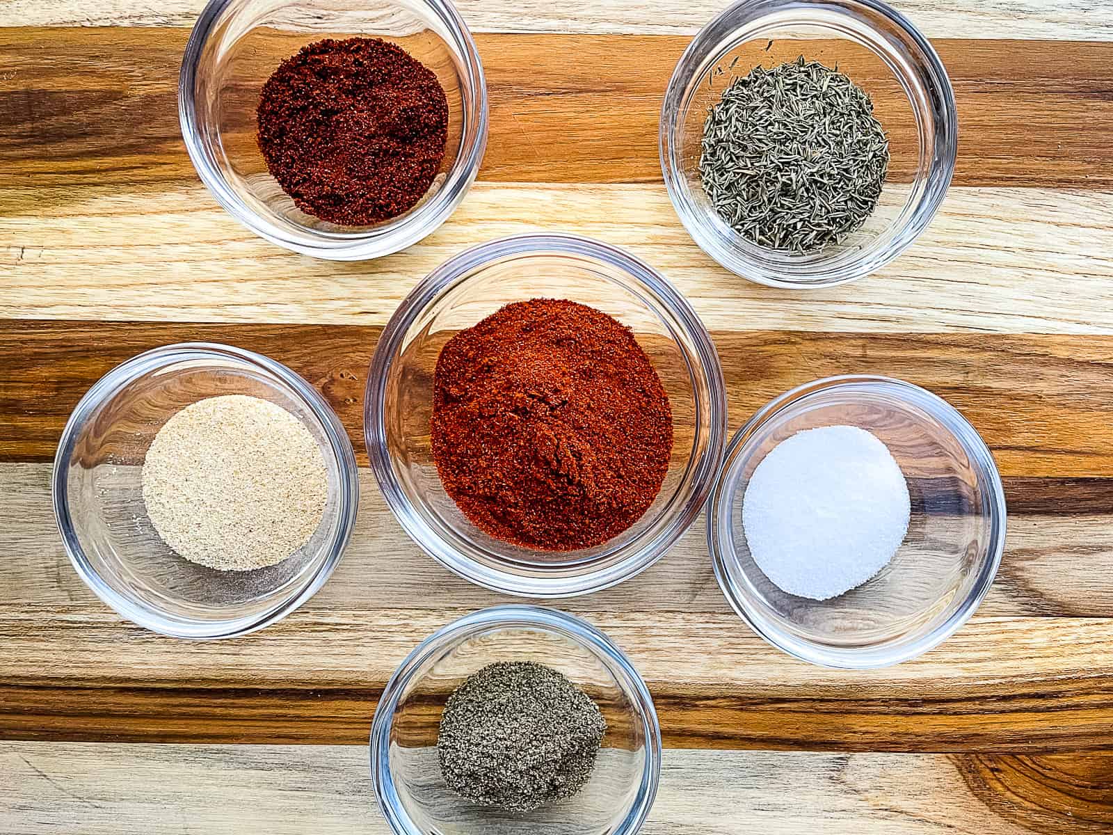 Smoked chicken rub ingredients in individual glass bowls.