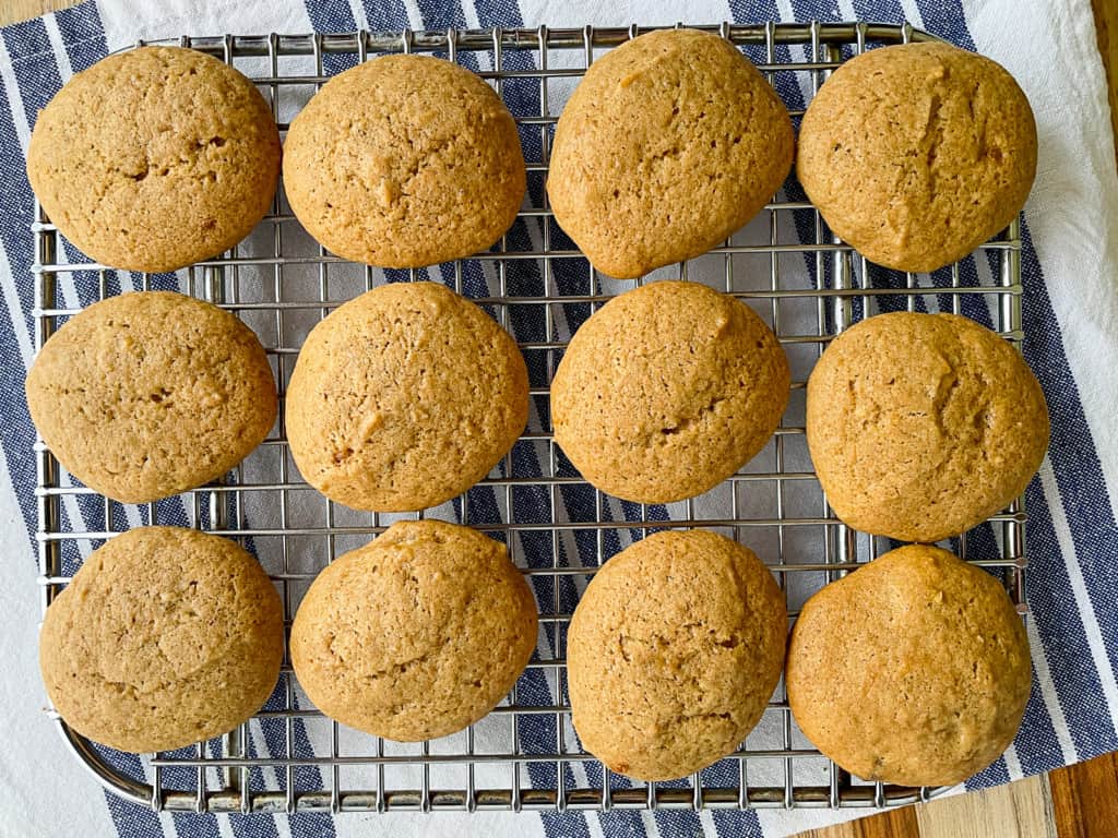 Soft banana cookies cooling on a wire rack. A blue and white towel is under the rack.