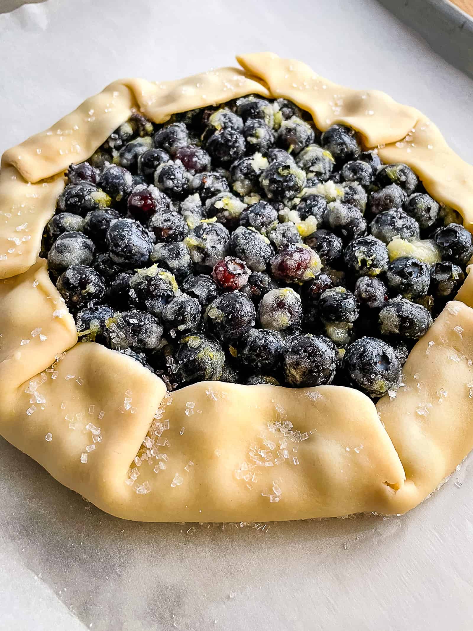 Unbaked blueberry galette on a baking sheet.