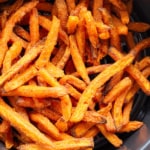 Cooked frozen sweet potato fries in an air fryer basket.