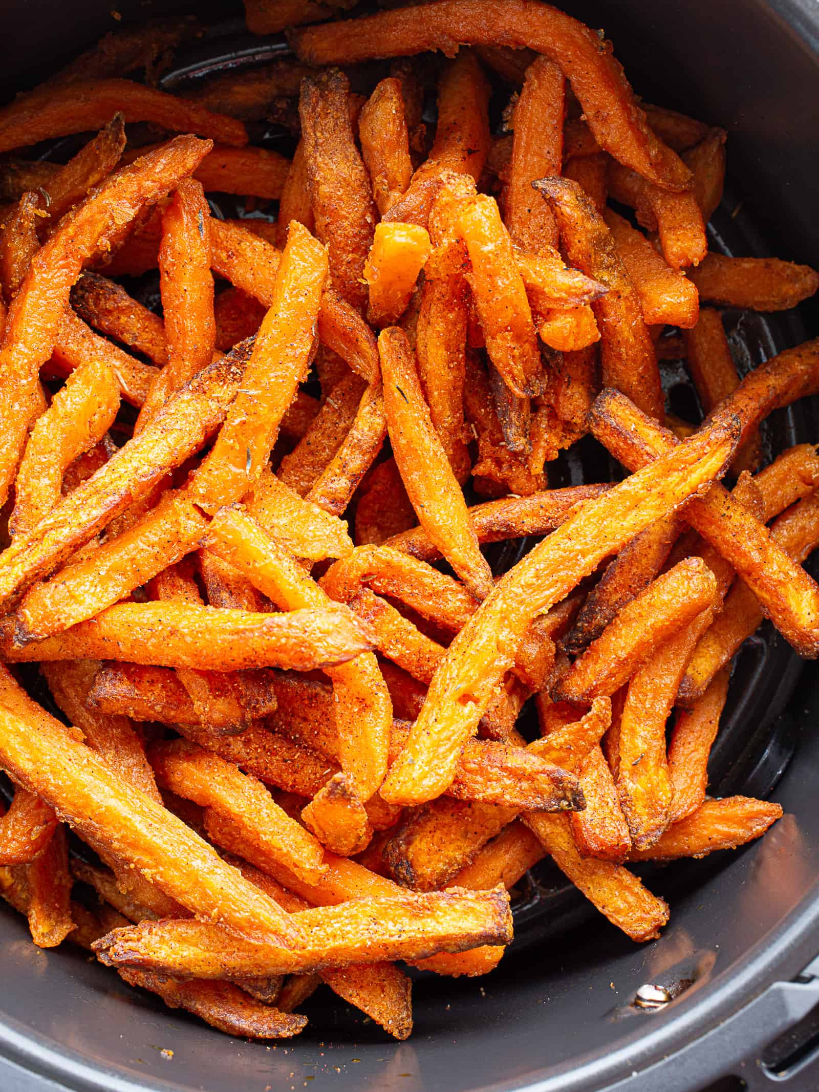 Cooked frozen sweet potato fries in an air fryer basket.