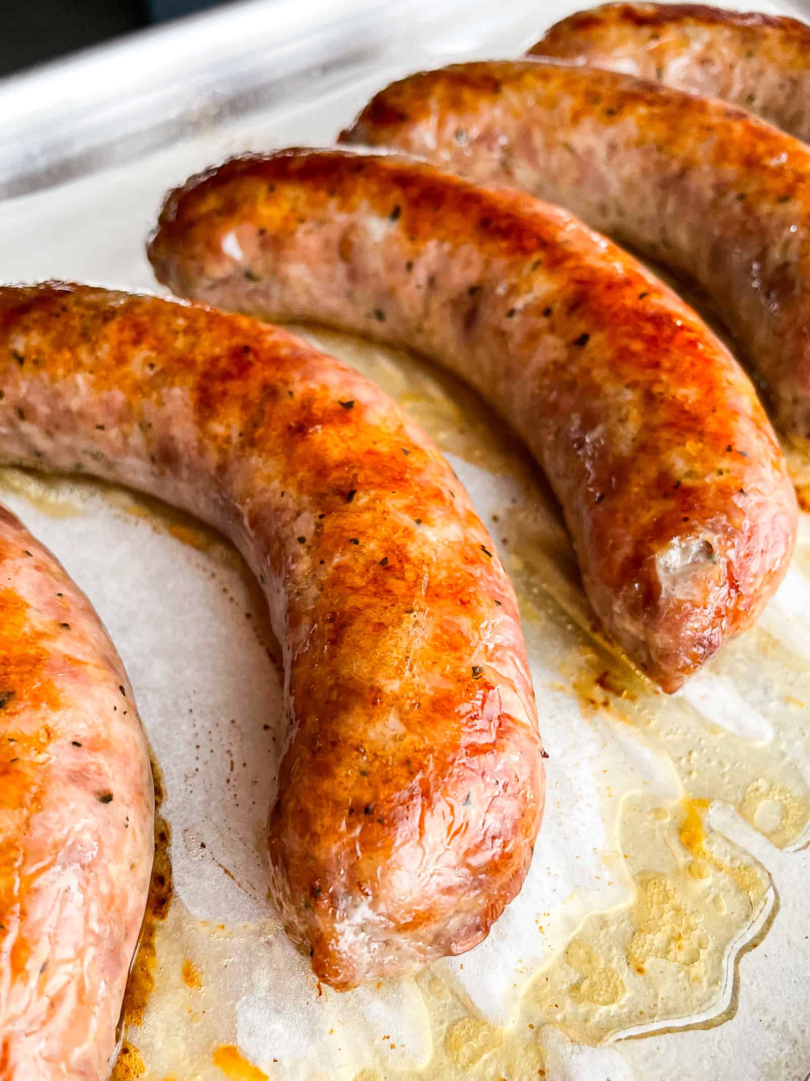 Oven cooked sausage on a baking sheet.