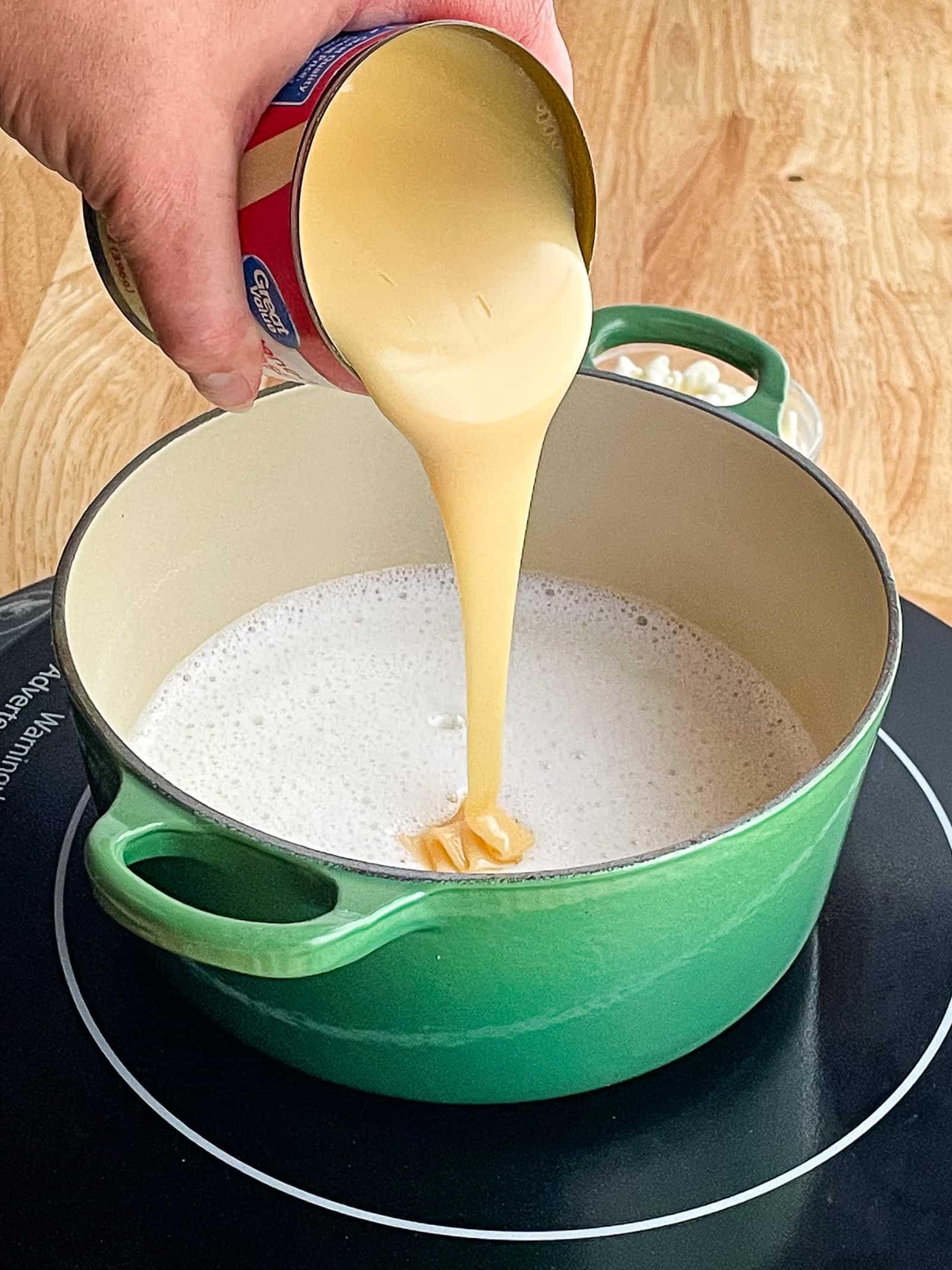 Adding condensed milk to white chocolate sauce.