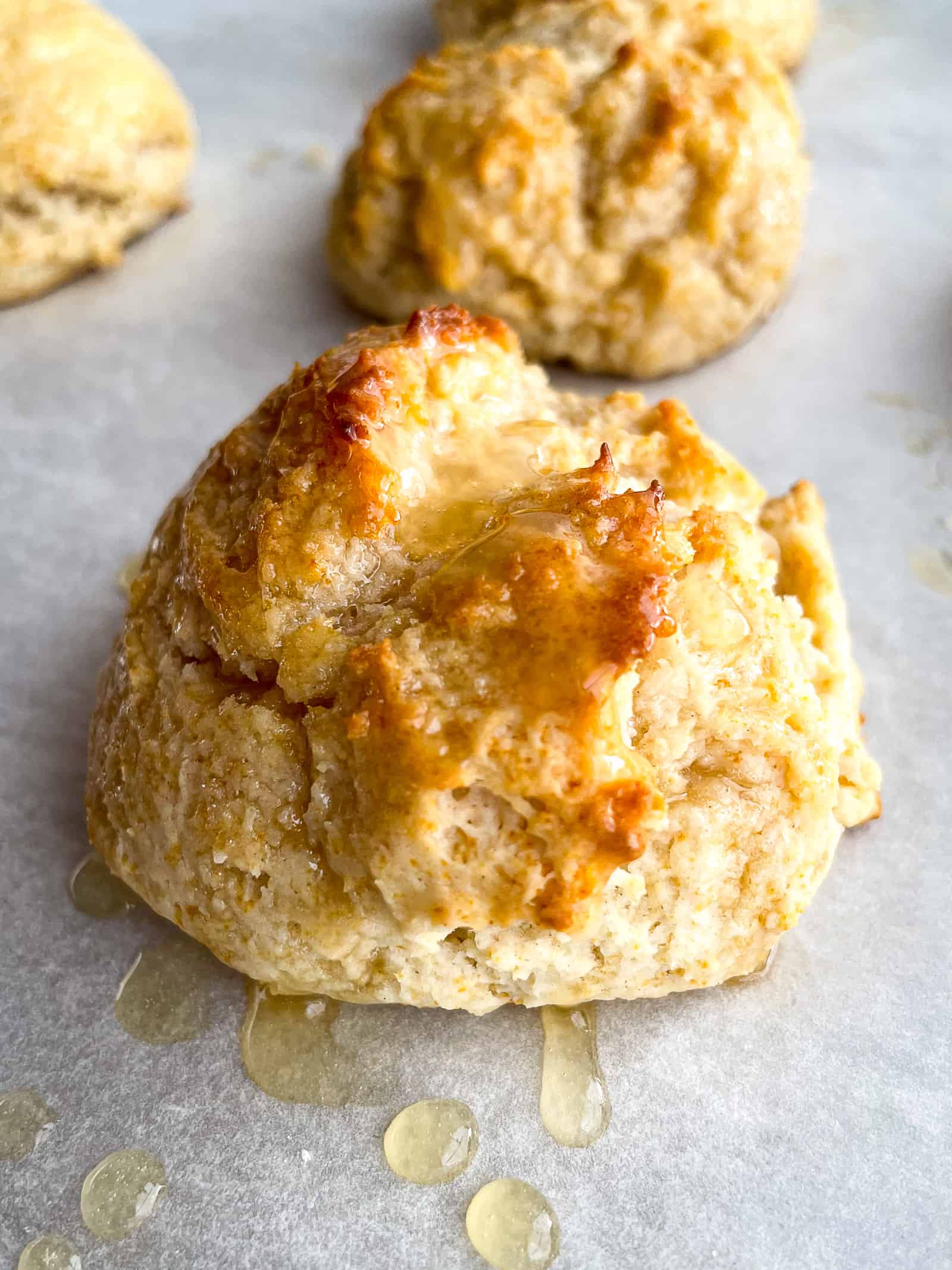 Honey butter biscuit with glaze on a sheet pan.