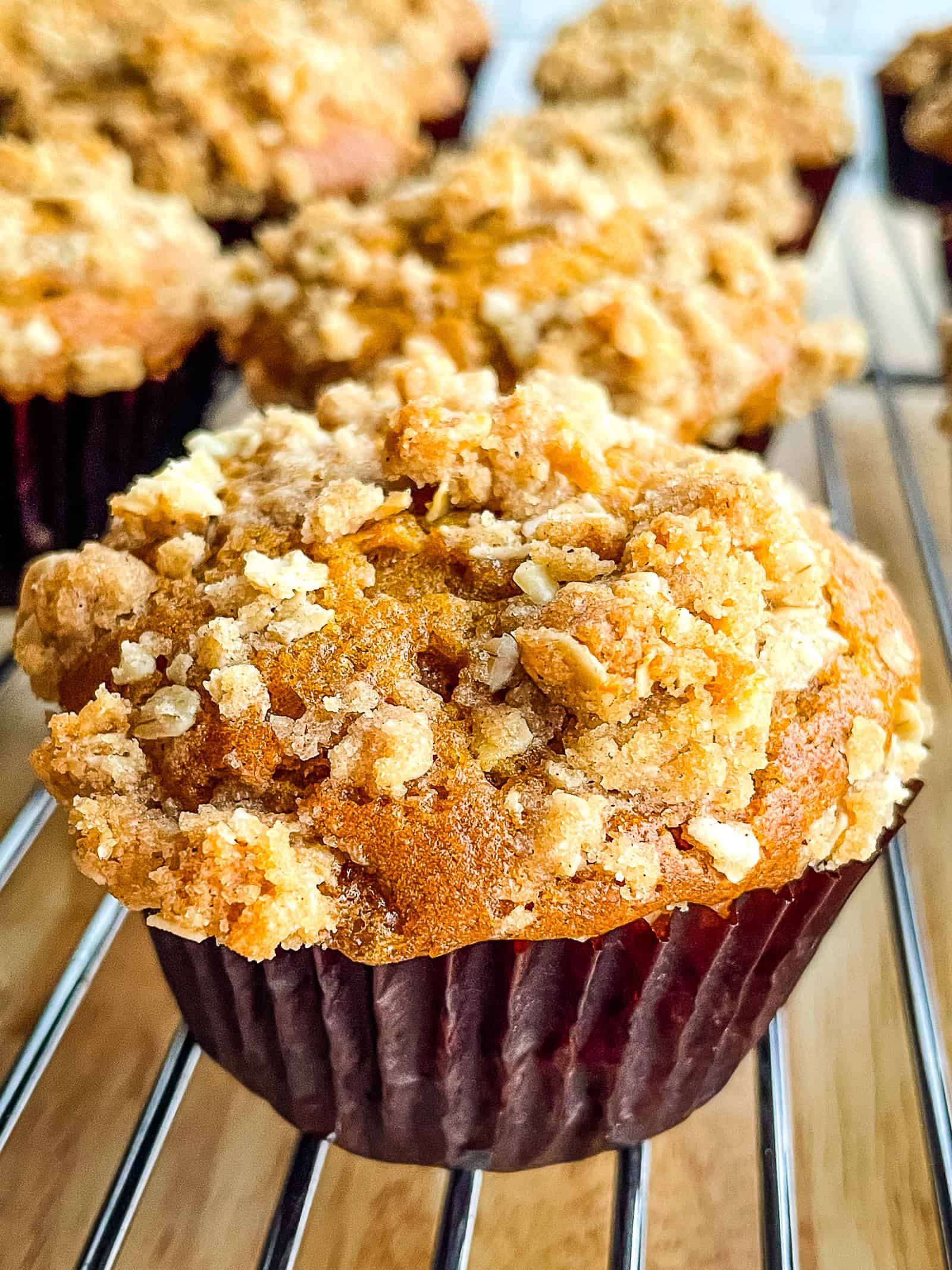 Pumpkin muffin with crumb topping on a wire rack.