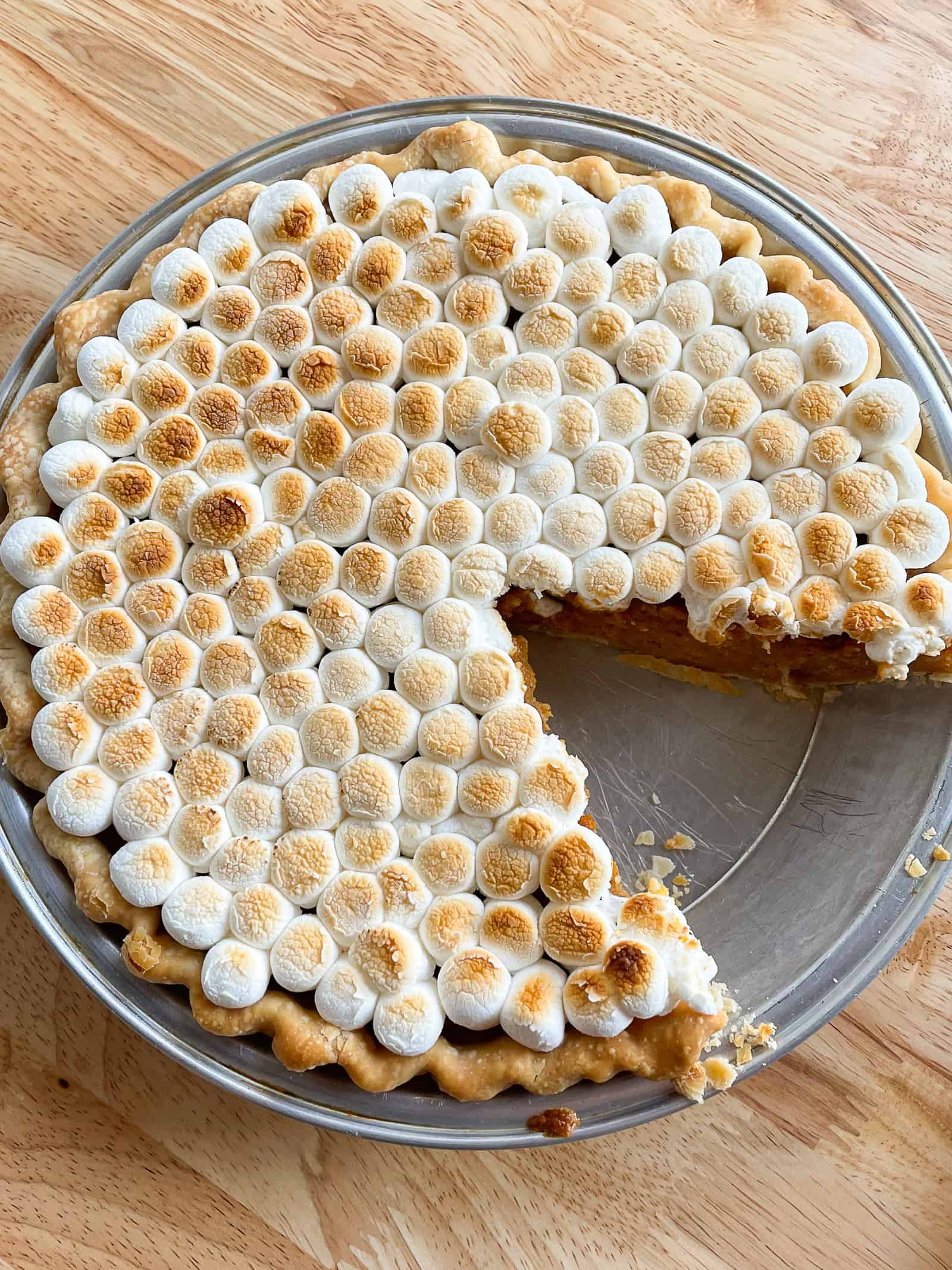 Sweet potato casserole pie topped with browned marshmallows. A slice has been removed from the pie. 