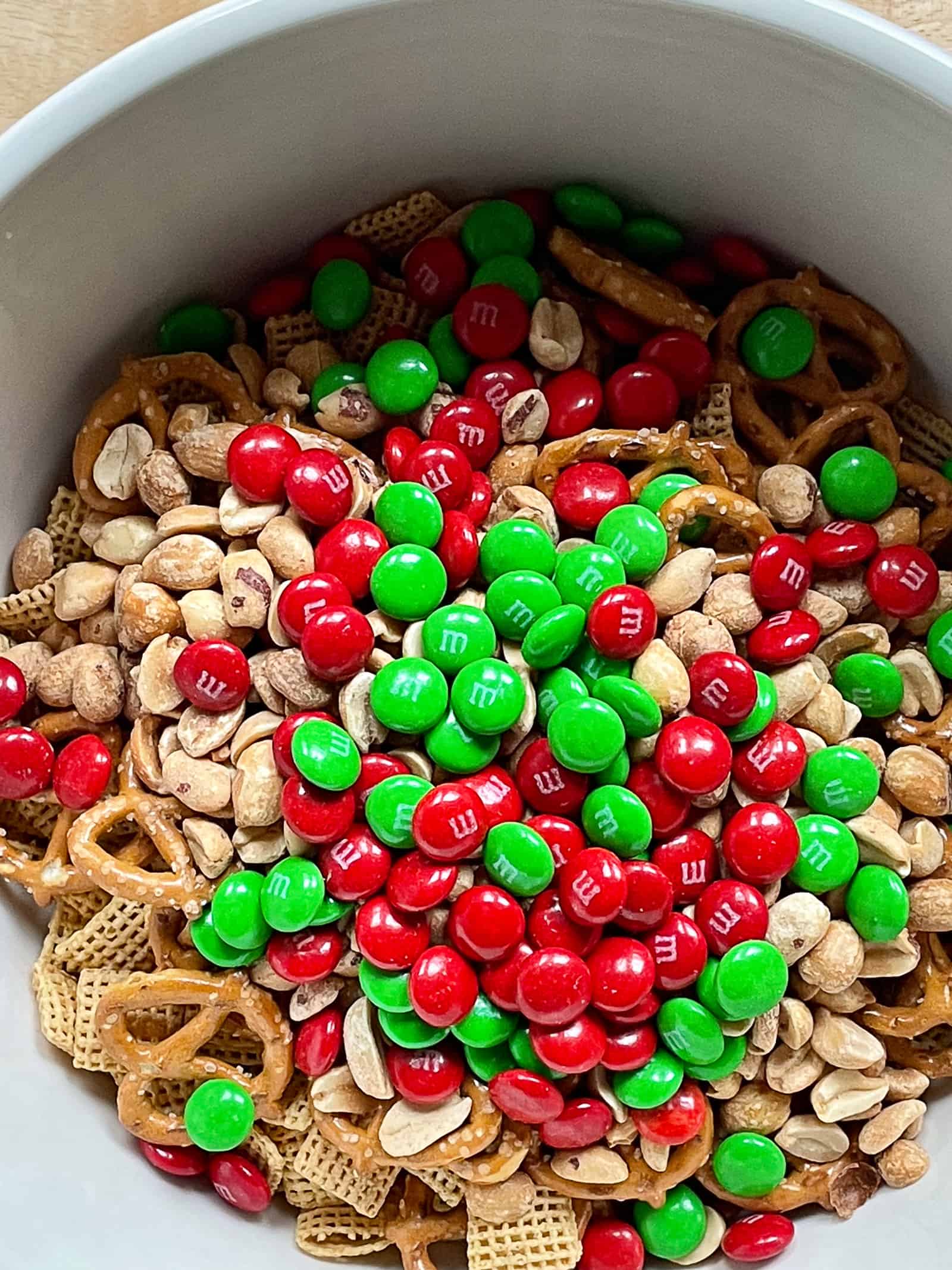 Bowl of Cinnamon Chex mix about to be stirred. M&Ms are sitting on top.
