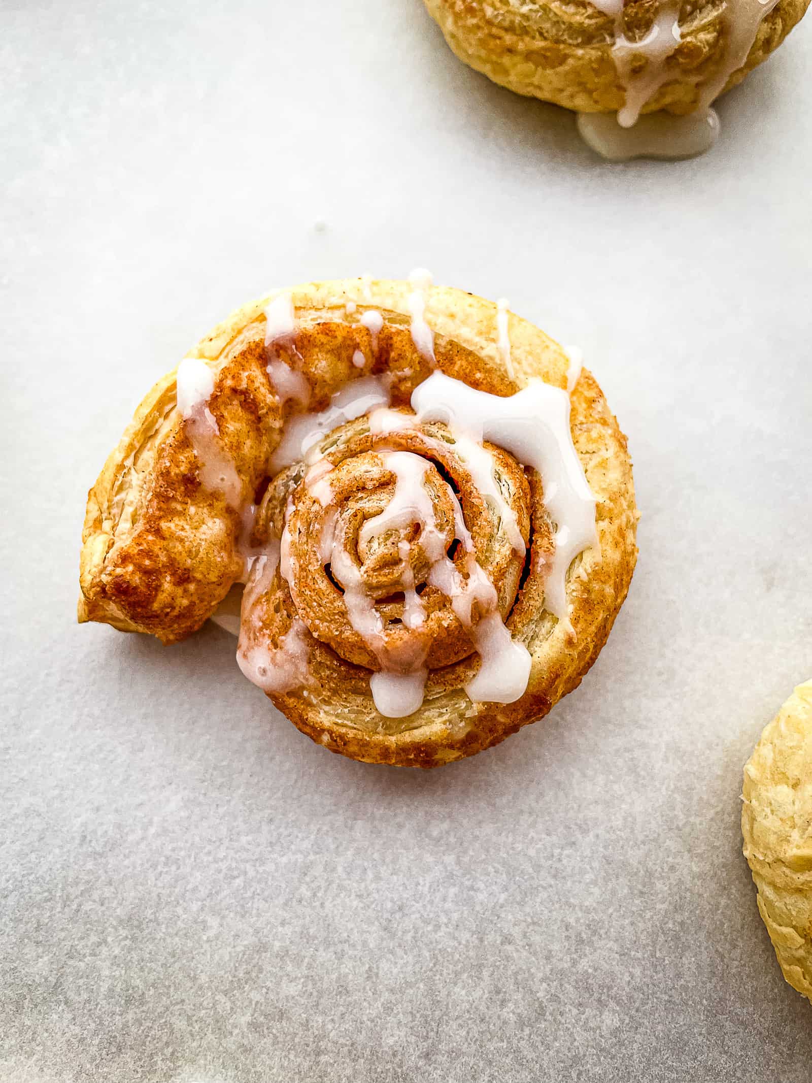 Puff pastry cinnamon roll with vanilla glaze.