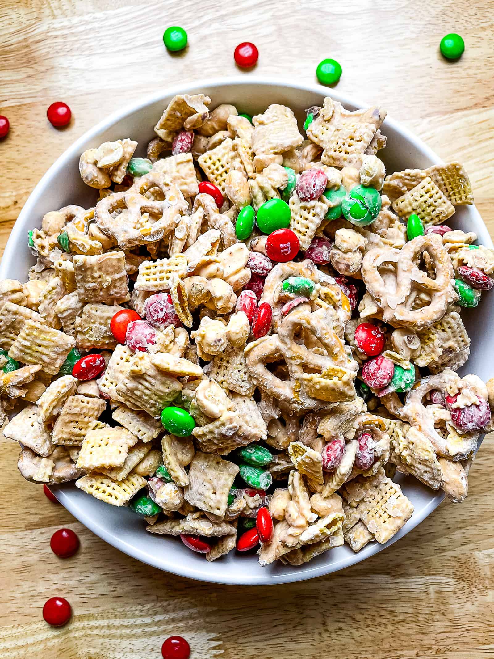 Cinnamon spiced Chex mix in a bowl. There are red and green M&Ms candy throughout the mix.