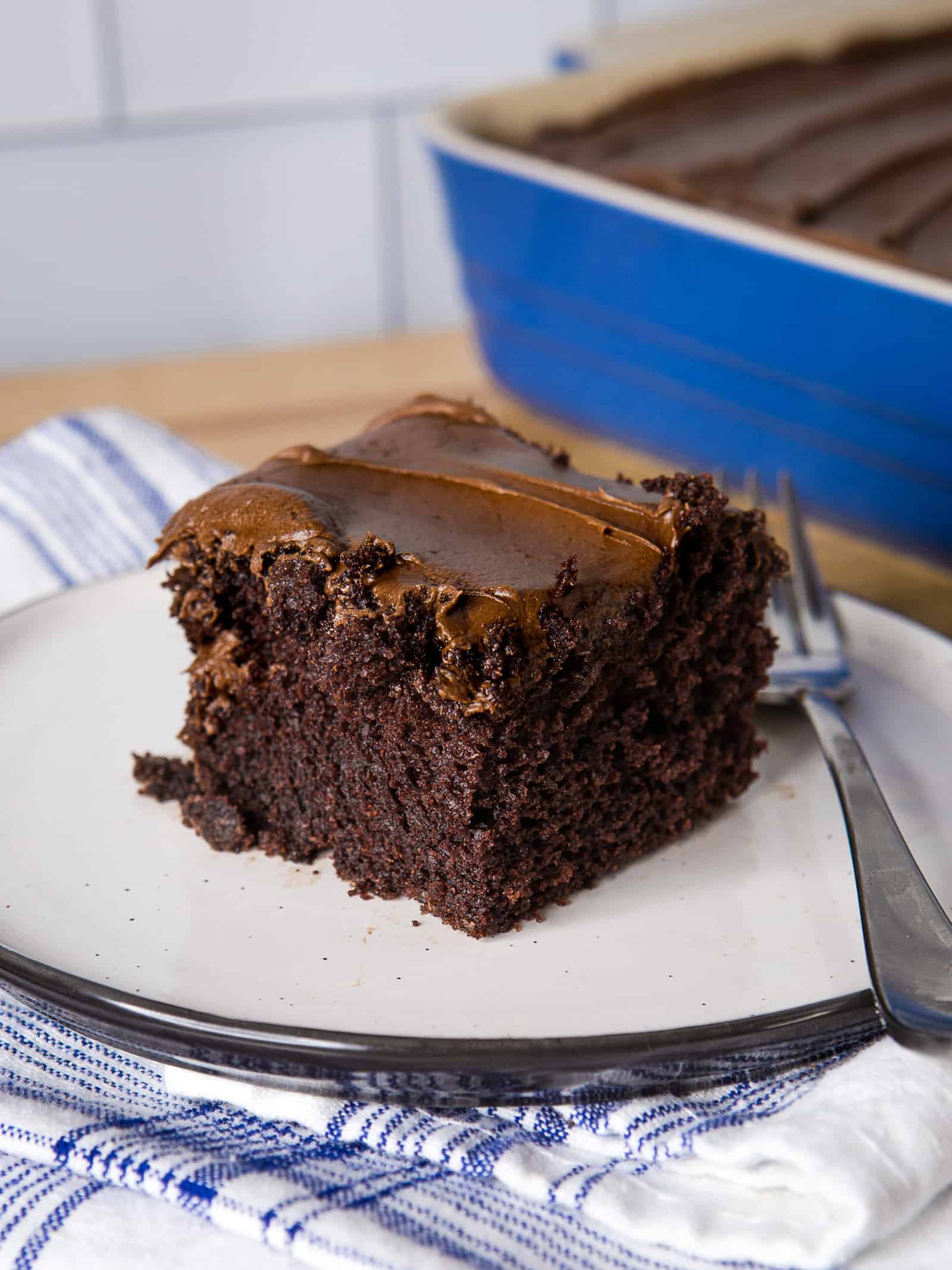 Slice of chocolate crazy cake on a plate. The cake is frosted with chocolate buttercream.