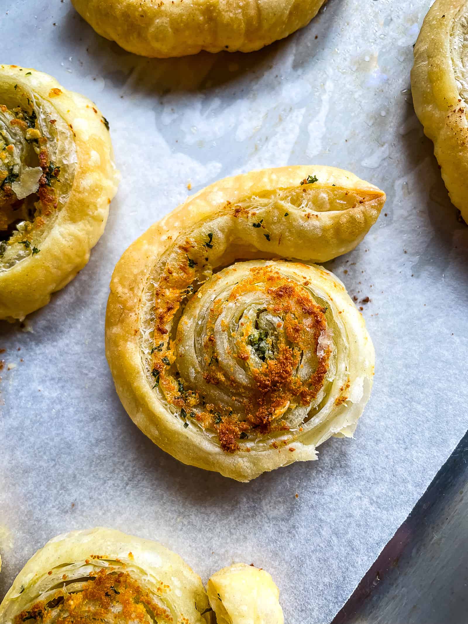 Garlic puff pastry swirl baked and cooling on a pan.