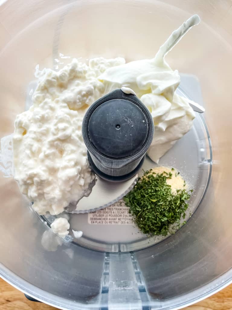 Cottage cheese, sour cream, and spices in a food processor for cottage cheese dip.