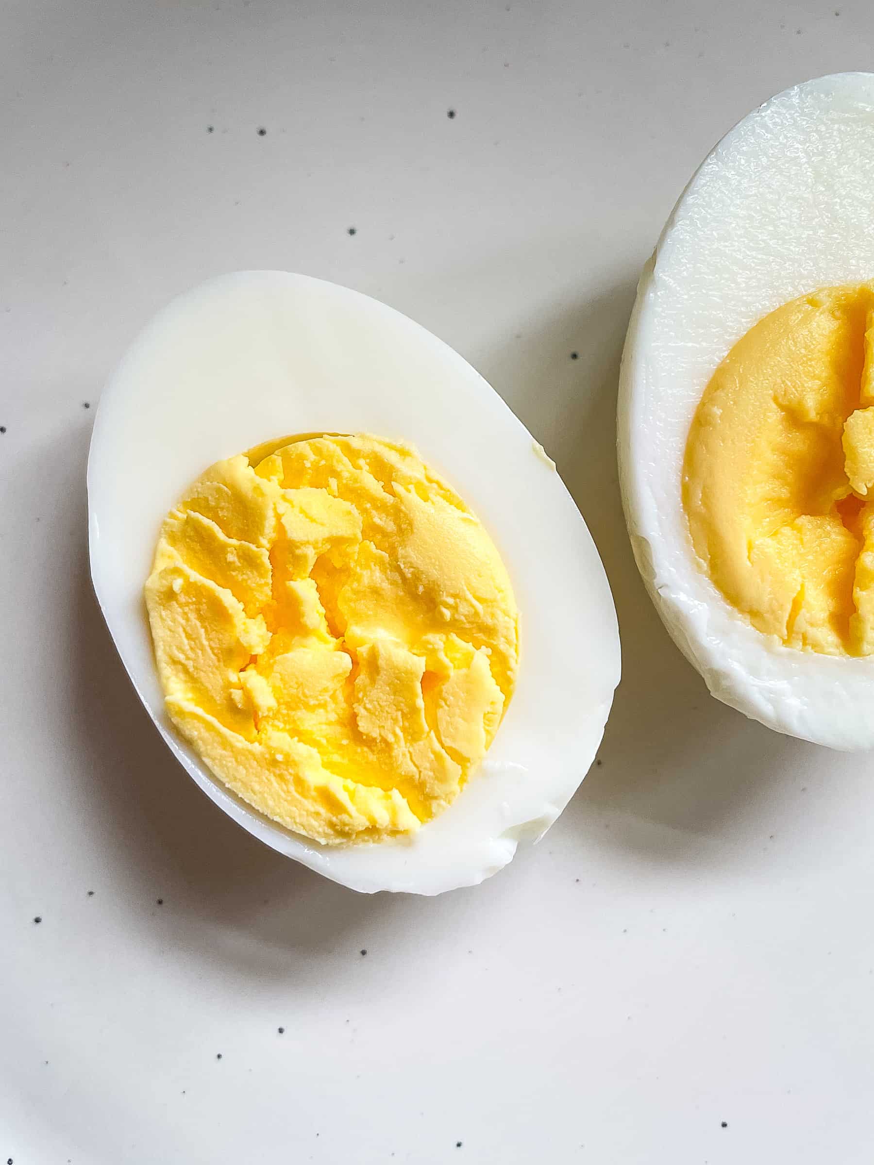 One hard boiled egg cut in half on a plate.