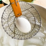 Placing a hard boiled egg in an ice bath.