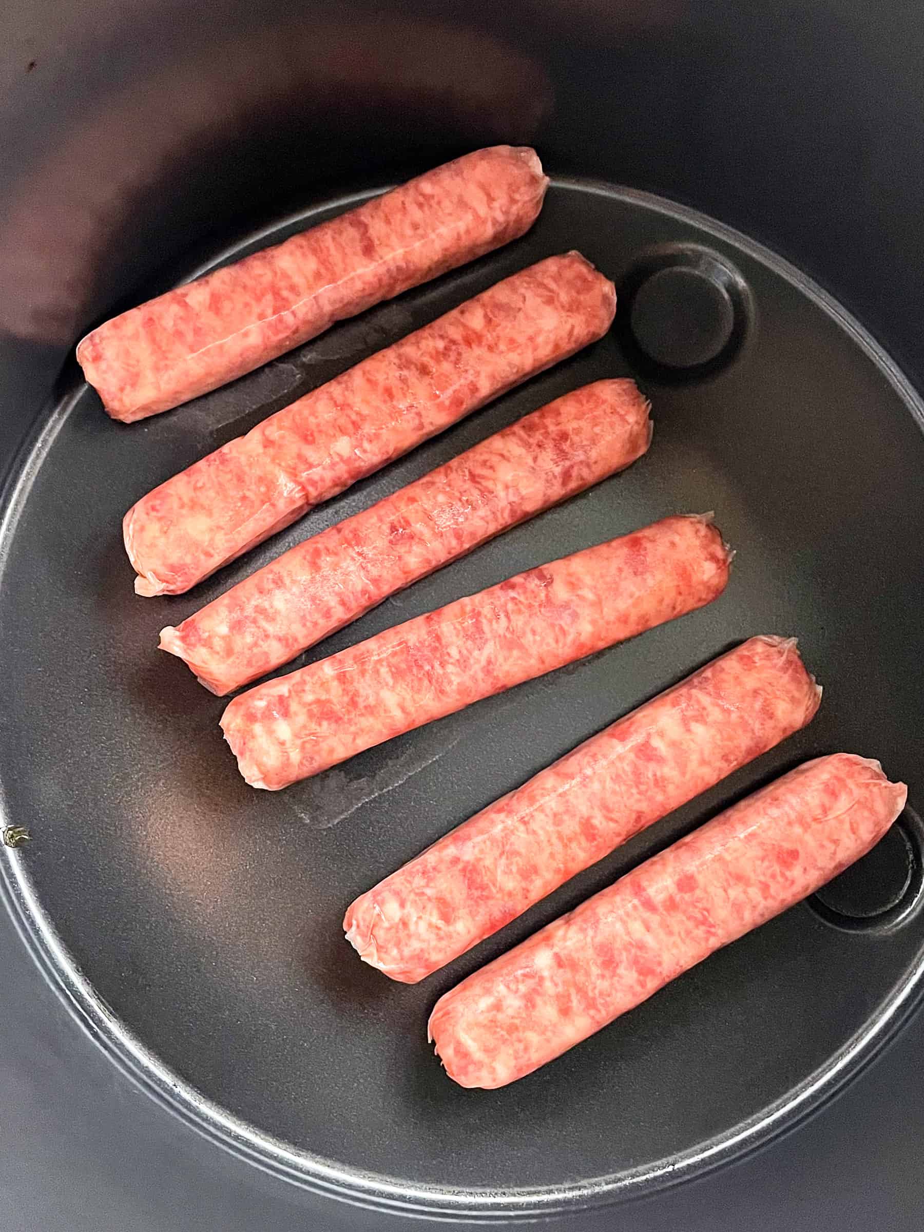 Fresh, uncooked breakfast sausage links in an air fryer pan.