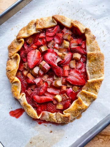 Strawberry rhubarb galette cooling on a baking sheet.