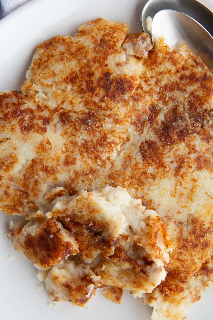 Closeup of fried mashed potatoes on a white plate.