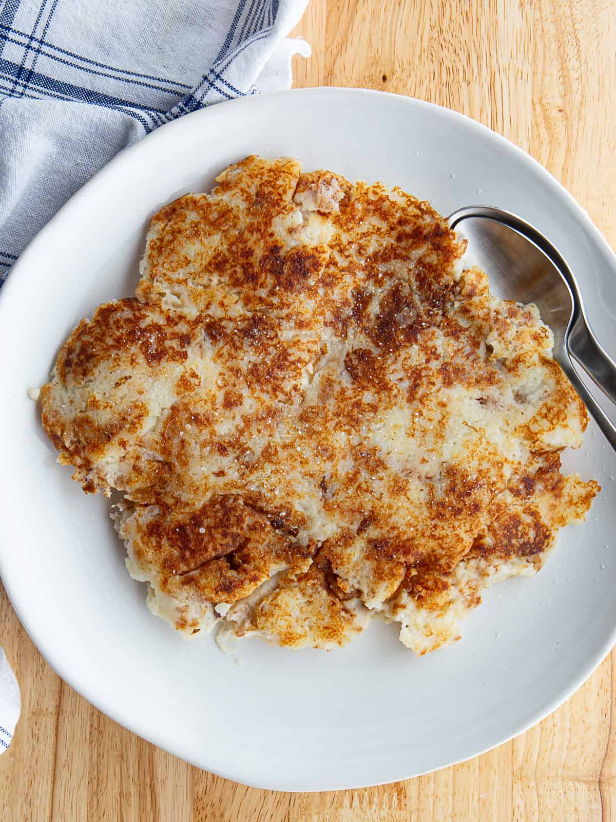 Fried mashed potatoes on a white plate sprinkled with a little Kosher salt.