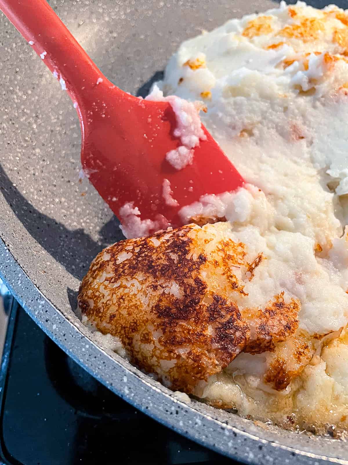 Fried Mashed potatoes in a skillet. Bottom is brown and crispy.