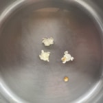 Three popped popcorn kernels and one un-popped kernel in hot coconut oil.