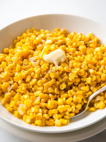Frozen corn cooked with onion and topped with black pepper and butter.