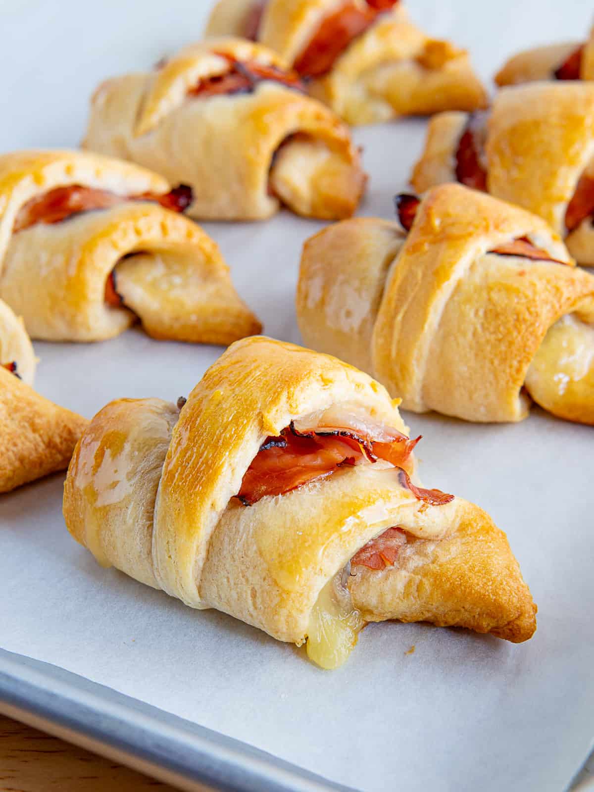Ham and cheese crescent rolls cooling on a baking sheet.