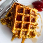 Stuffing waffles drizzled with maple syrup and leftover cranberry sauce on a plate.