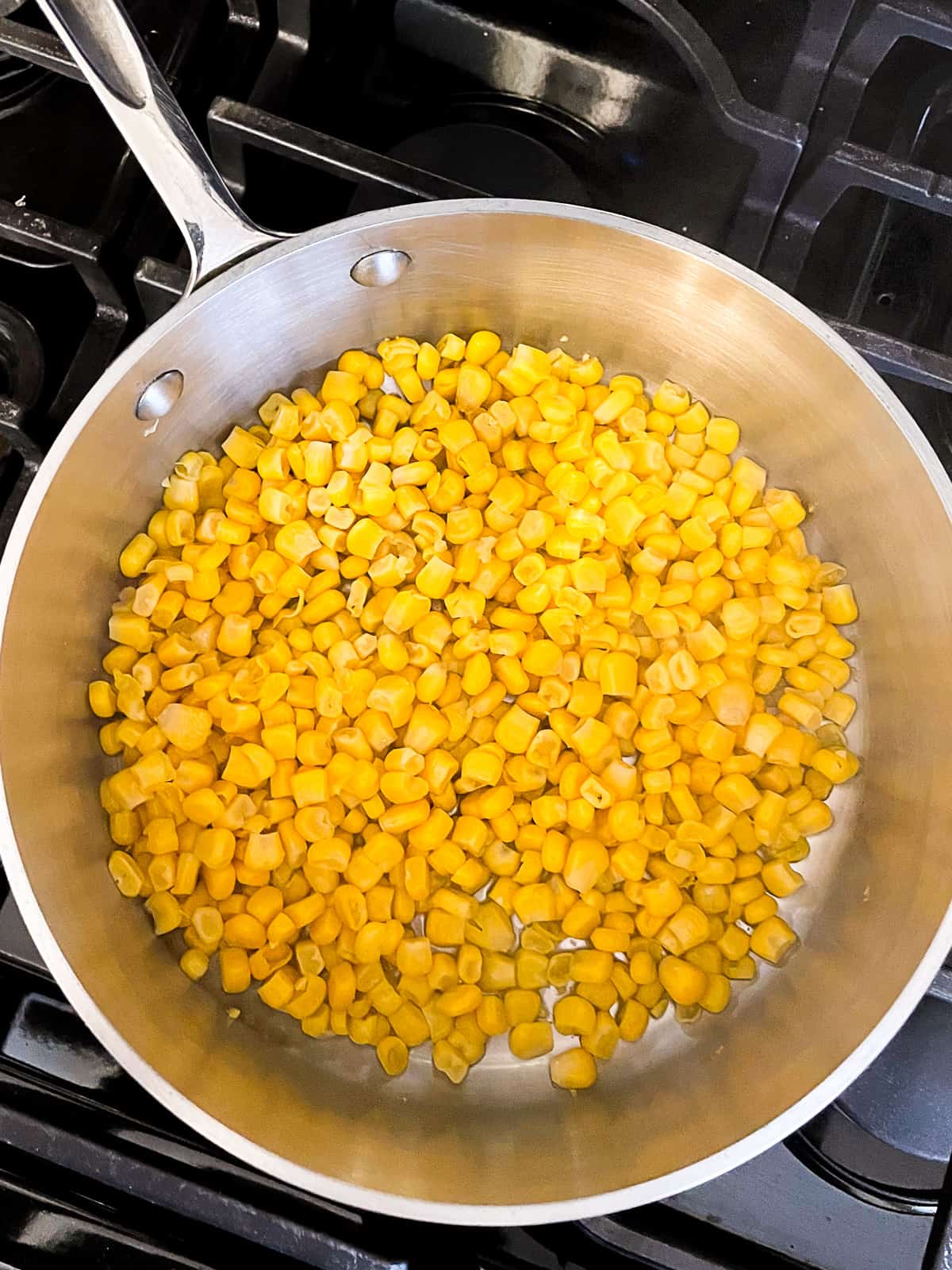 Cooking canned corn in a small pan.