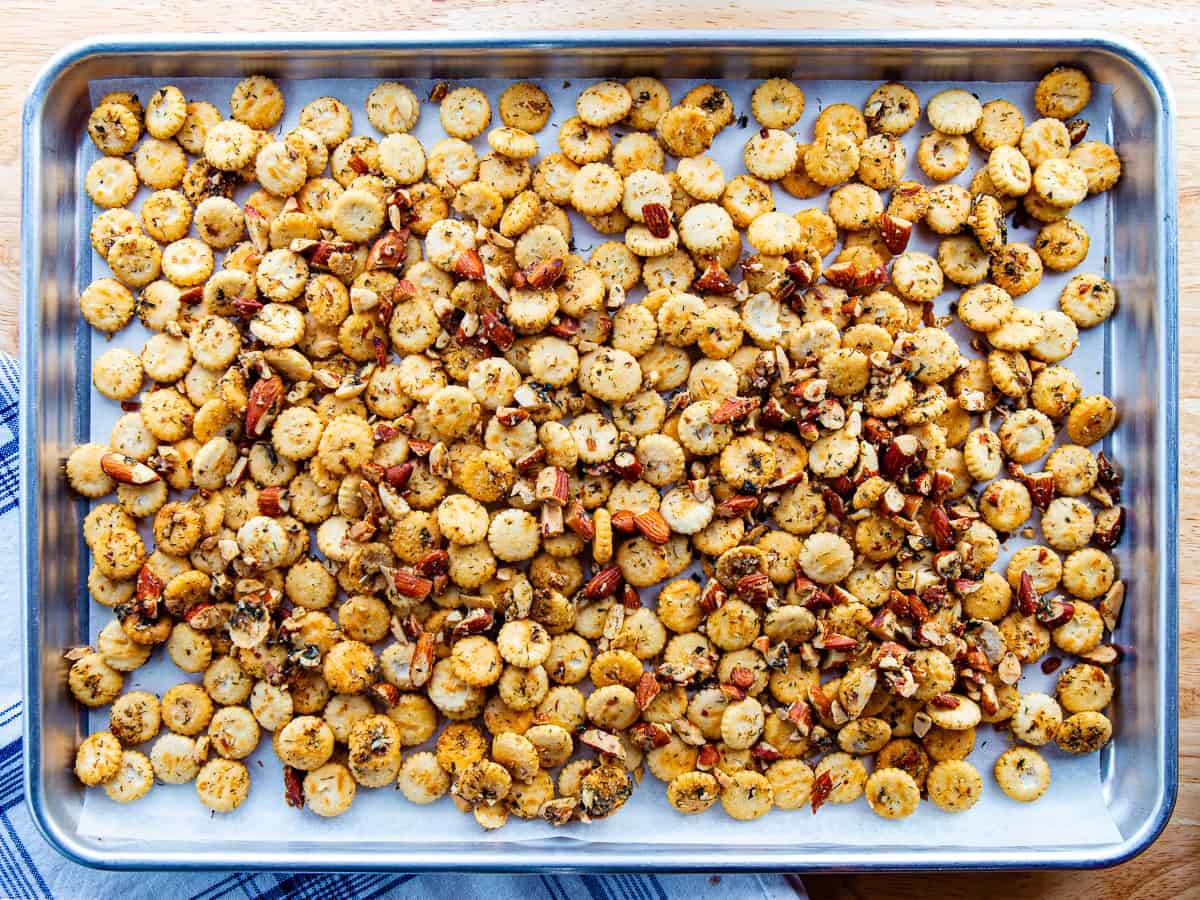 Seasoned oyster crackers and nuts on a baking sheet.