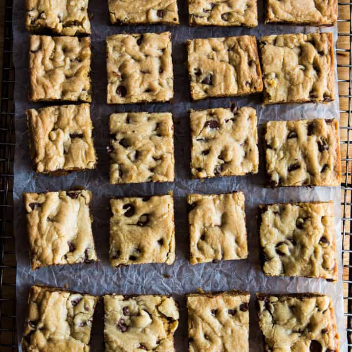 Chocolate chip cookie bars on cooling rack with parchment underneath.