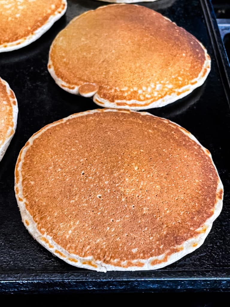 Oat flour pancakes cooked on a griddle.