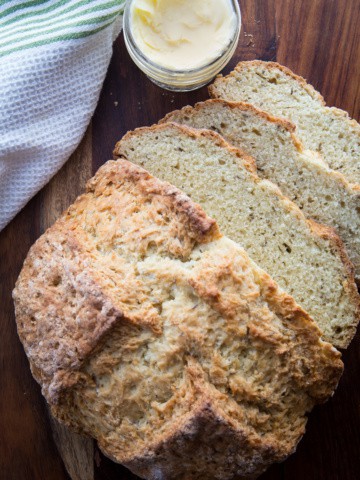 Caraway Irish soda bread sliced on a cutting board with a small jar of butter next to it.