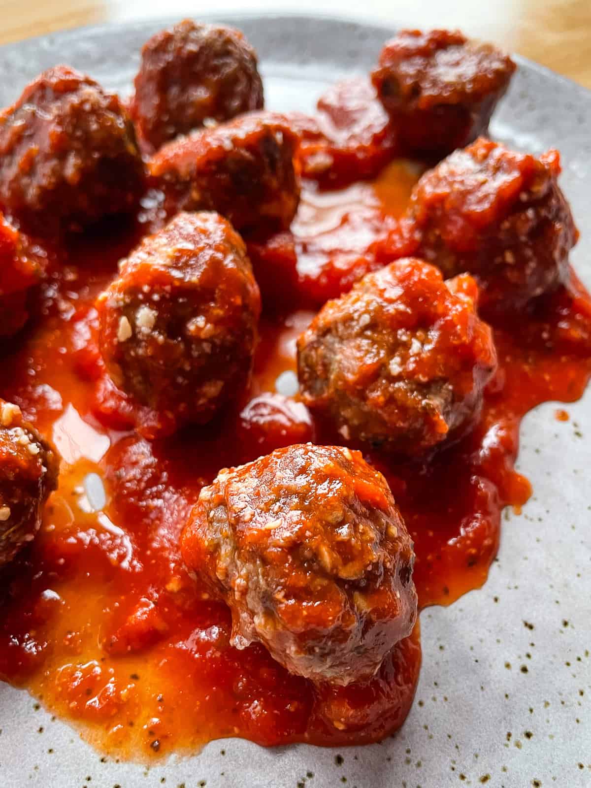 Baked meatballs on a plate covered with pasta sauce.