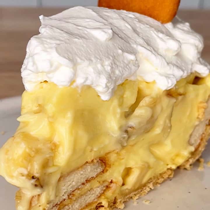 Slice of banana pudding pie topped with whipped cream and a vanilla wafer.