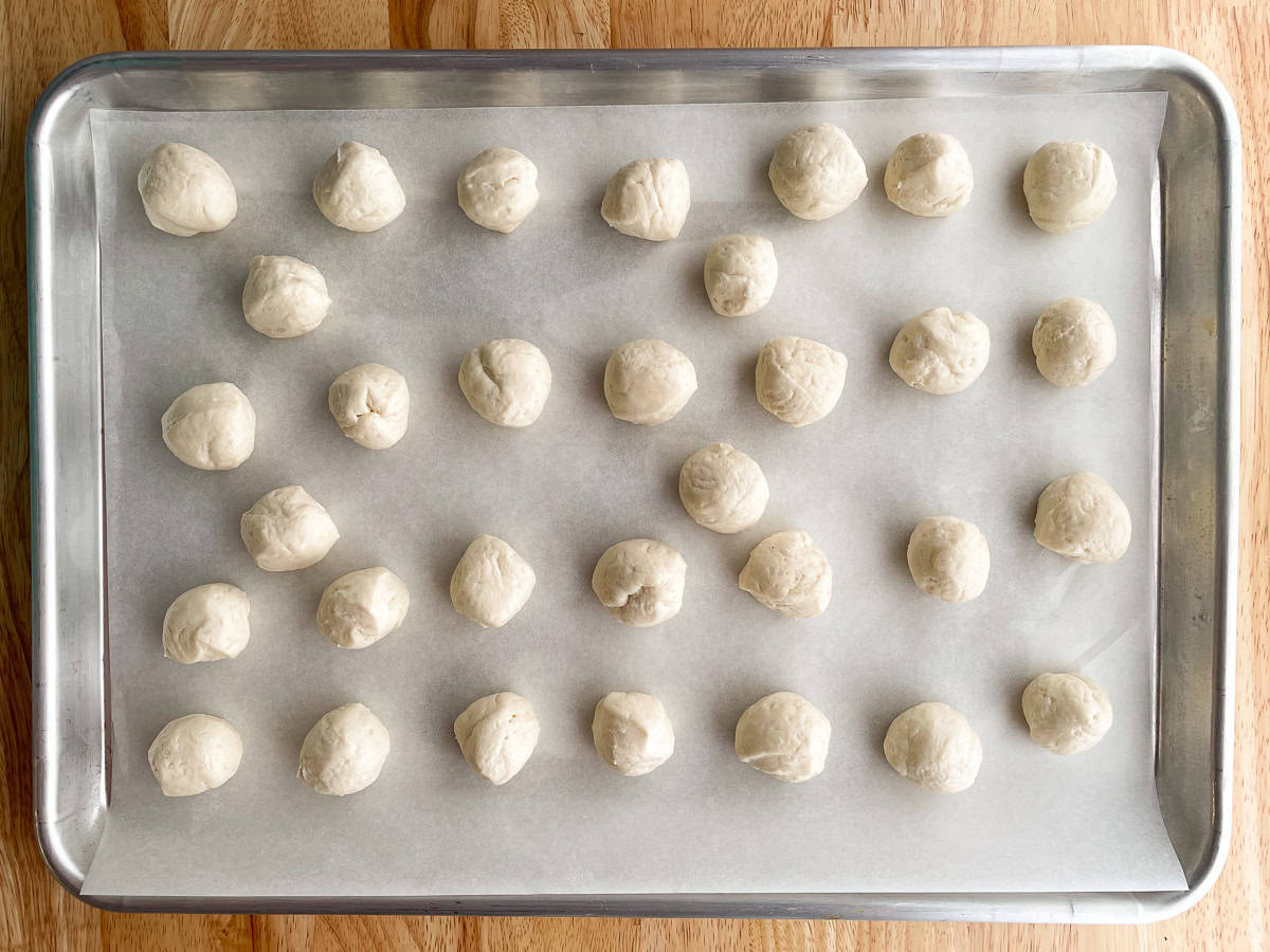 Canned biscuits rolled into balls on a baking sheet.