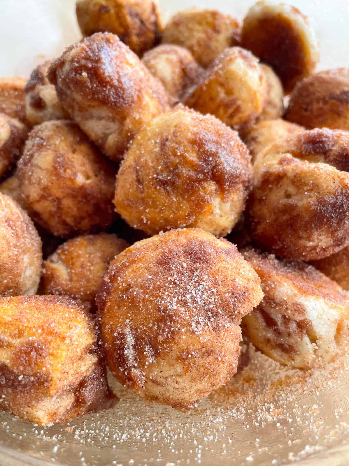 Cinnamon sugar biscuit donut holes in the mixing bowl.