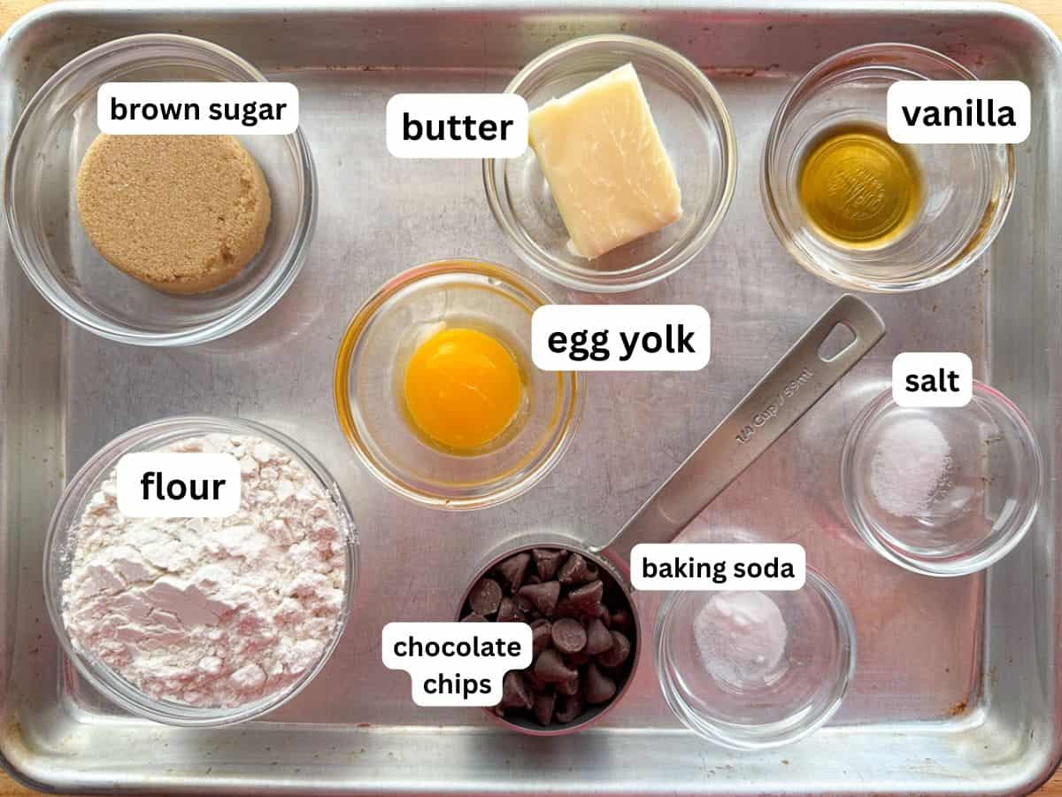 Ingredients for a small batch of chocolate chip cookies measured and in bowls on a small sheet pan.