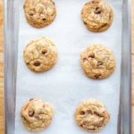 Six chocolate chip cookies on a small baking pan.