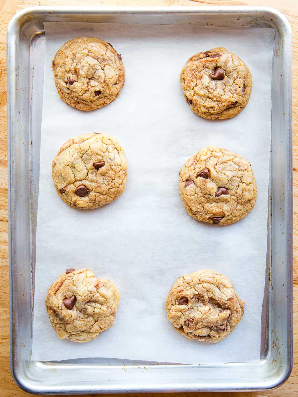 Six chocolate chip cookies on a small baking pan.