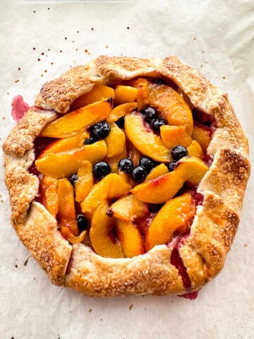 A peach-blueberry galette on parchment paper.