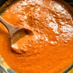 Tomato cream sauce in pan with wooden spoon.