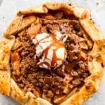 Apple galette with a scoop of ice cream in the center and a drizzle of caramel sauce.