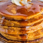 A stack of pumpkin pancakes with butter and syrup.