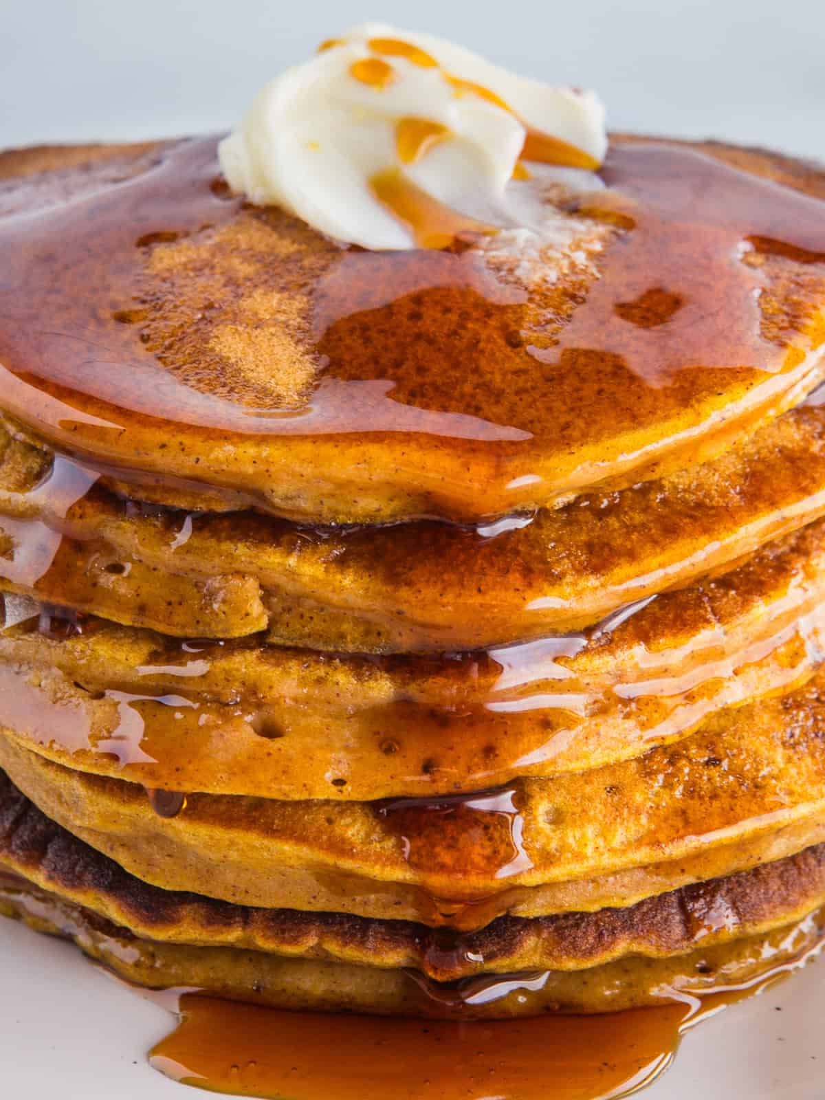 Closeup of a stack of pumpkin pancakes with butter and syrup.
